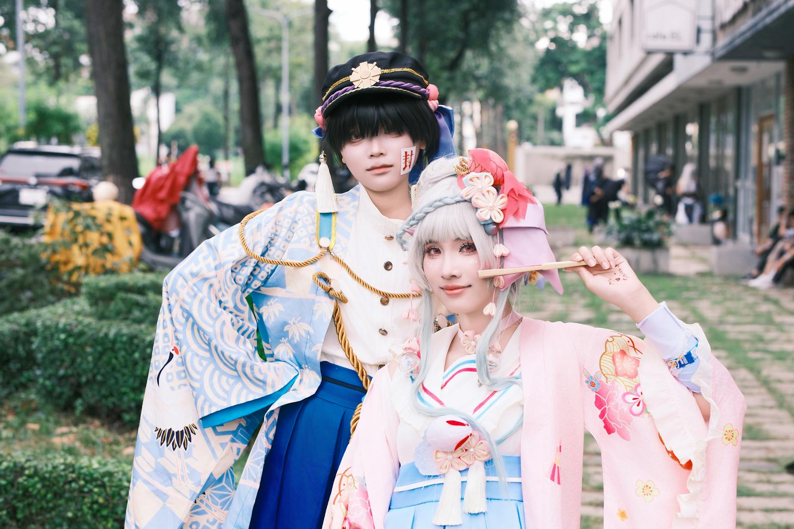 Two cosplayers in traditional Japanese attire posing outdoors with vibrant costumes.
