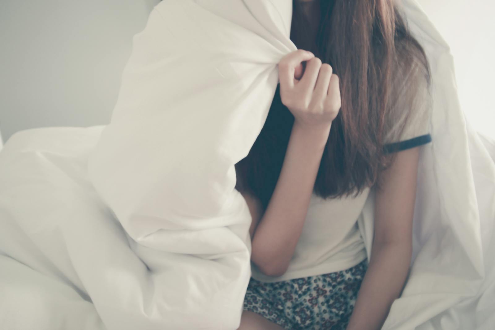 Cozy morning scene with a young woman relaxing under a blanket.