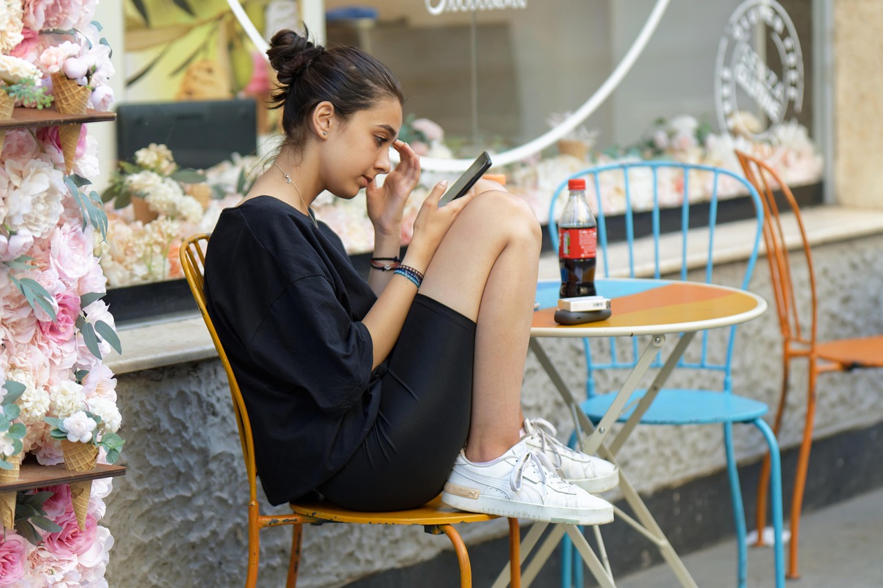 girl, sitting, casual, crouched, outdoors, looking, smartphone, cafe, woman