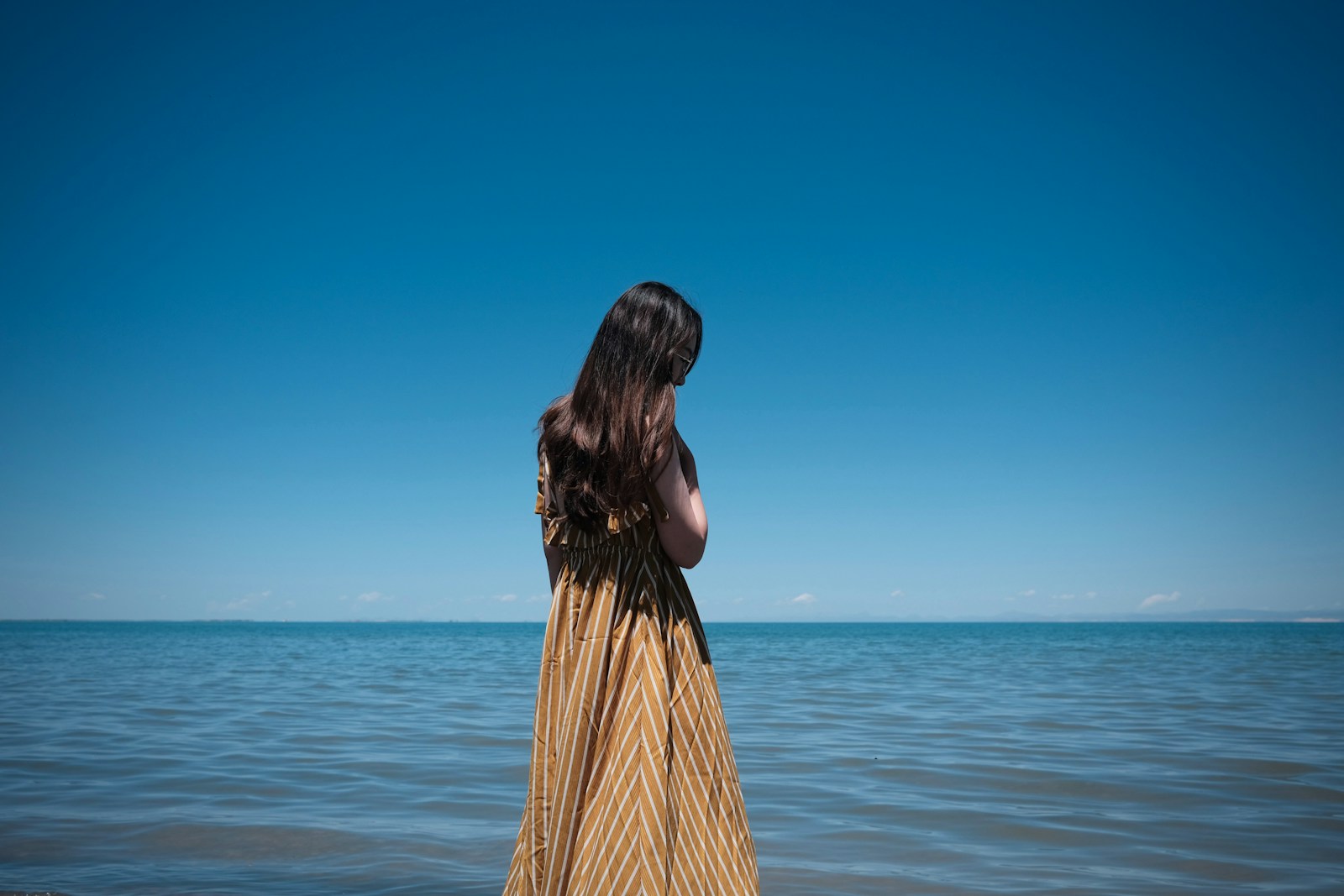 a woman standing in the water looking at the ocean
