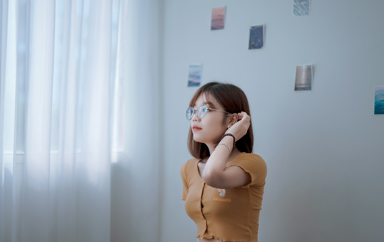 a woman wearing glasses standing in front of a window