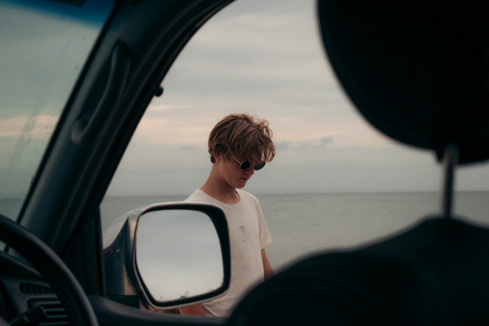 a man in a car looking out at the ocean