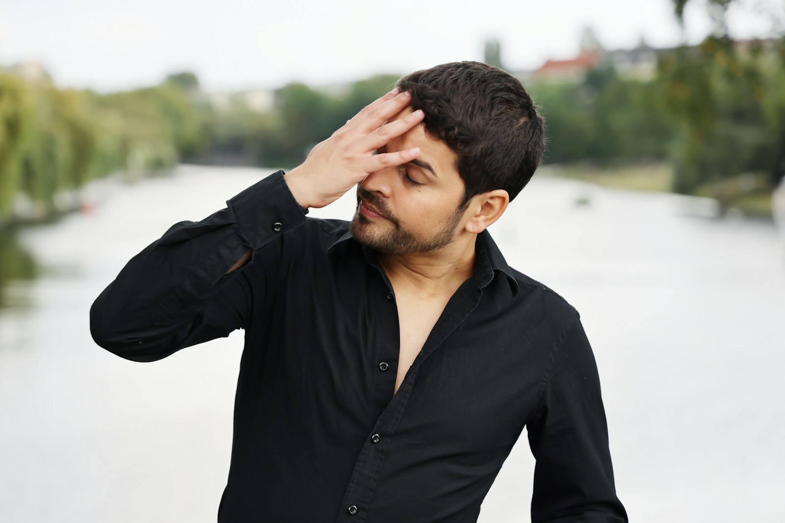 a man in a black shirt holding his hands to his head