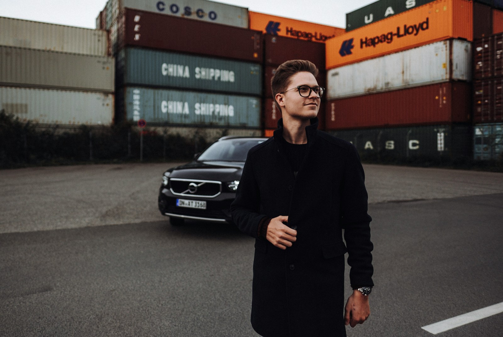man in black long sleeve shirt standing beside black car