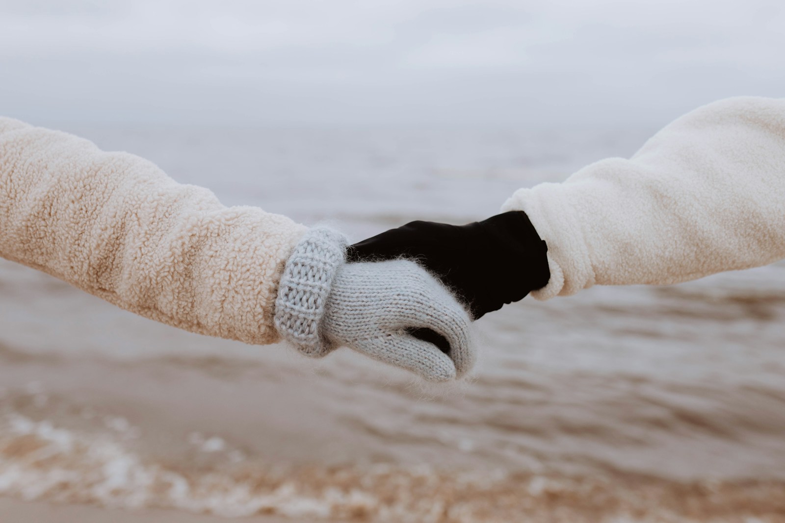 a pair of hands holding each other on a beach