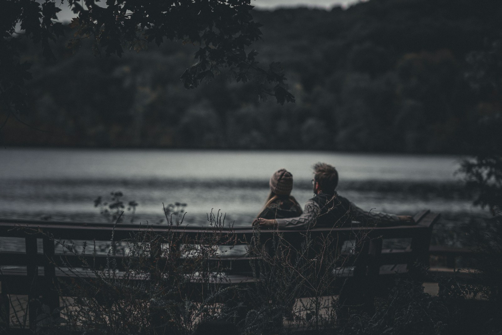 Two people sitting on a bench near a body of water