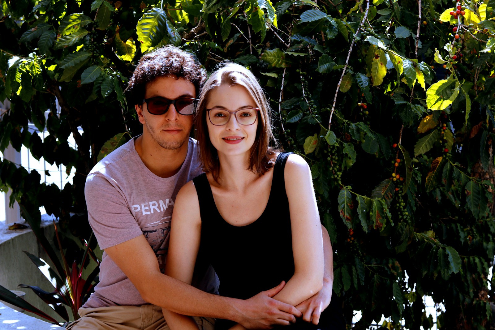 man and woman smiling near green plants