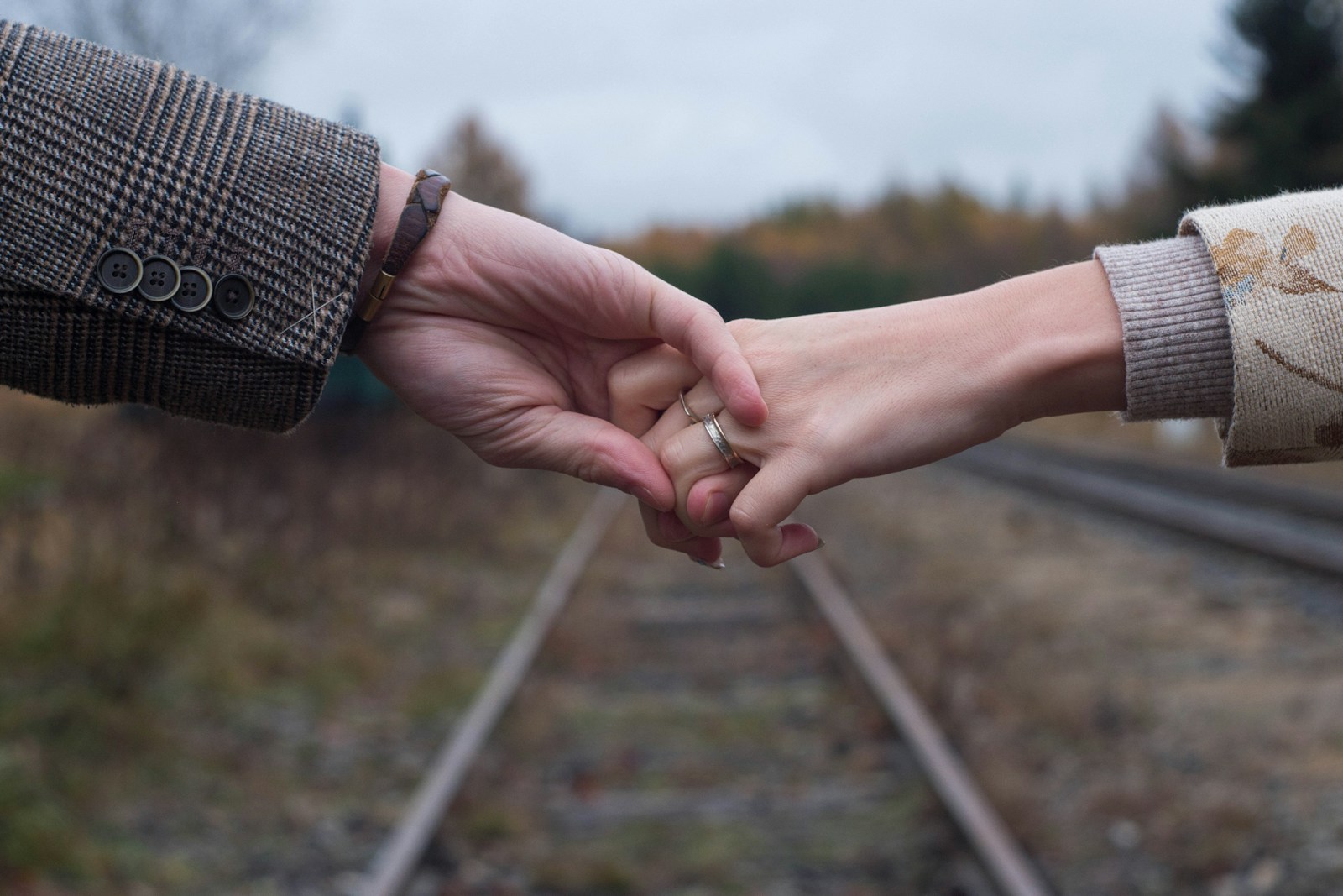 Two people holding hands on a train track