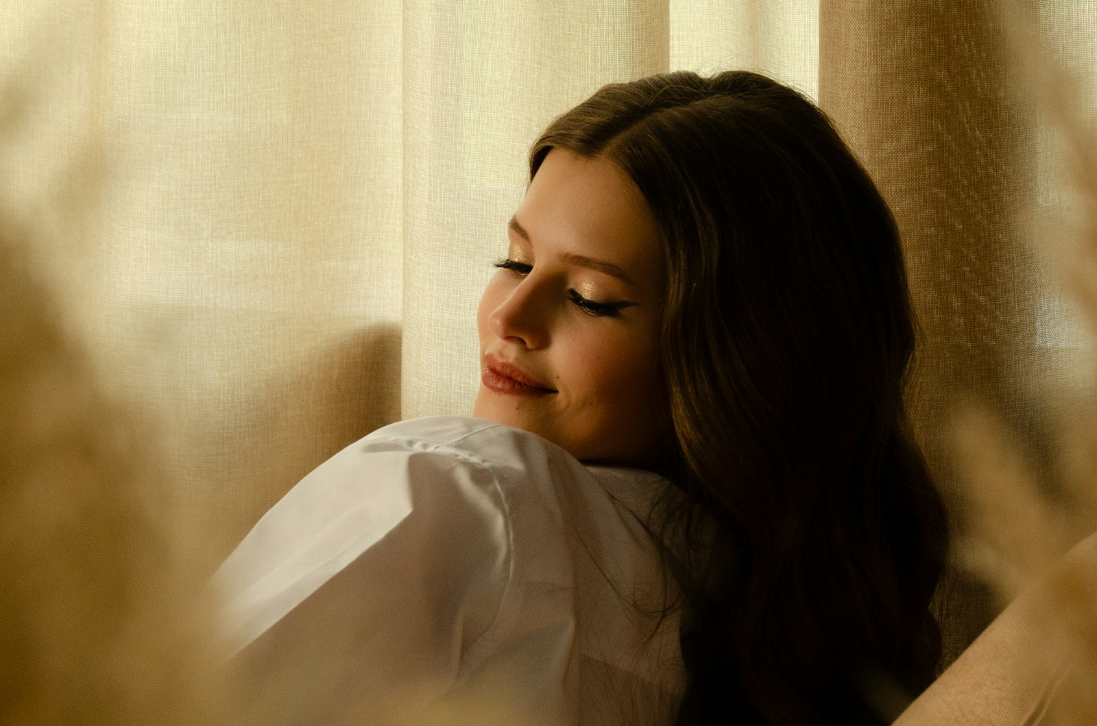 A woman sitting in front of a window with her eyes closed